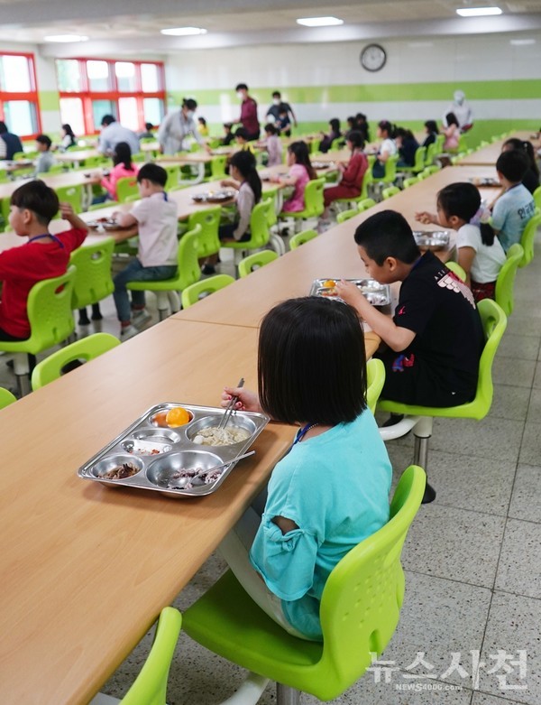 한 방향으로 앉아 점심을 먹고 있고 있는 초등학생들.