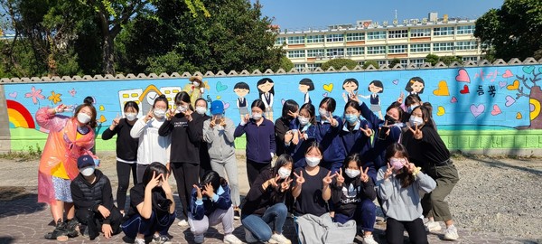 가온길 소속 학생들이 담벼락에 그린 벽화 앞에서 기념촬영을 하고 있다.(사진=사천여고)