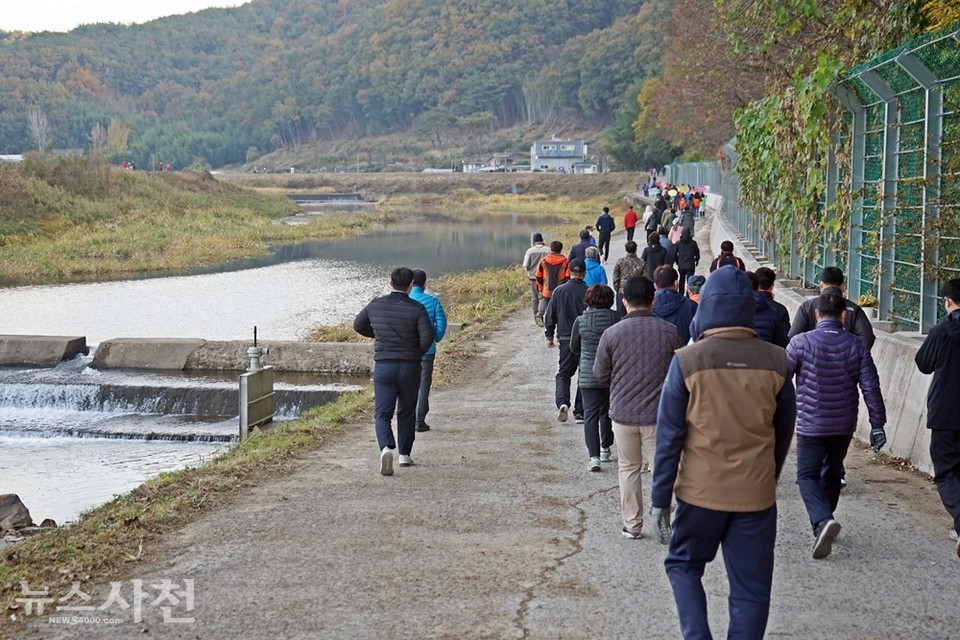 곤양천 둑방길을 따라 걷고 있는 사람들.