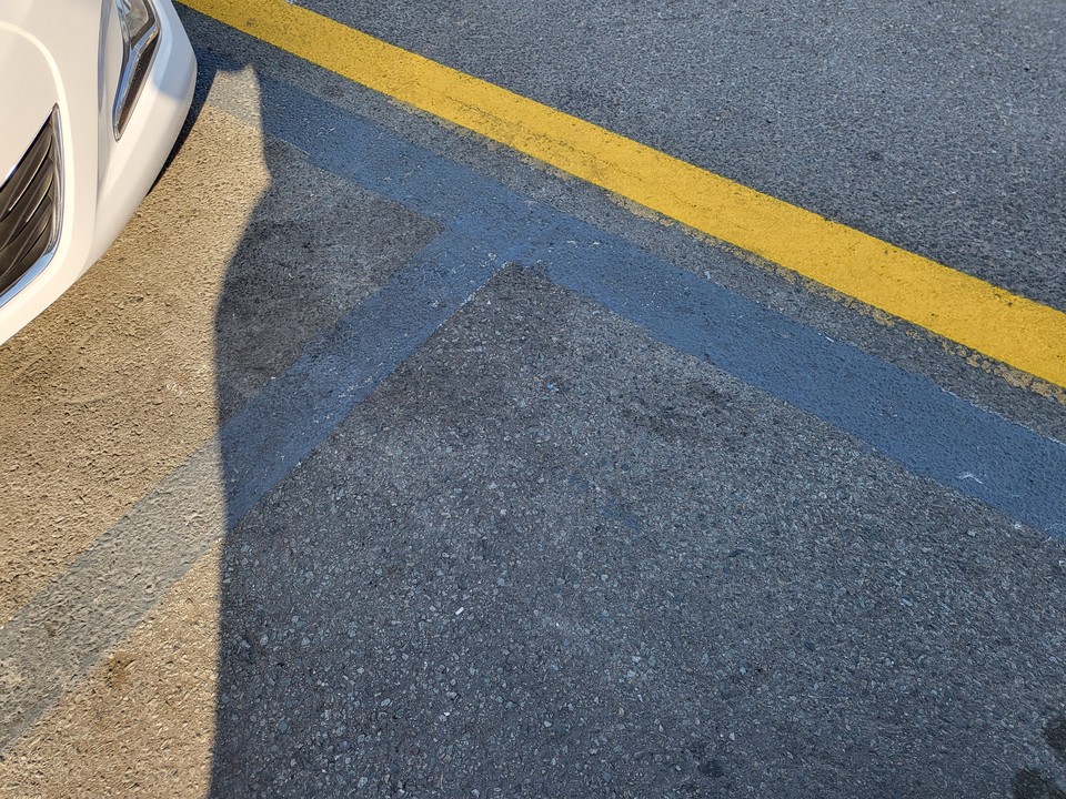 노상주차장의 표시였던 흰색 실선을 지우고, 그 옆으로 황색 실선이 그려져 있다.