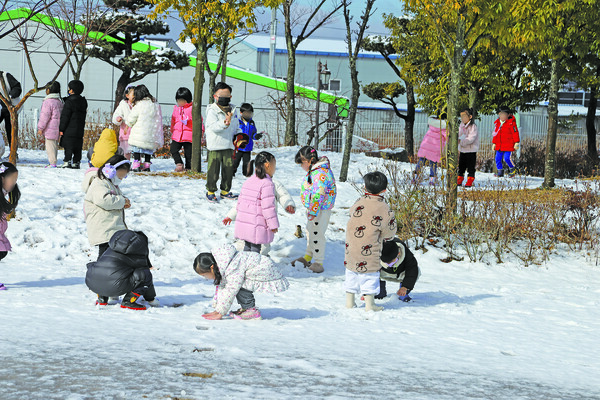 눈이 온 다음날 유치원 운동장에서 놀고 있는 아이들.